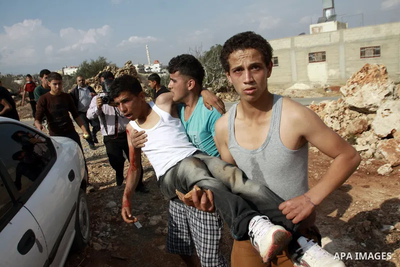 Palestinians carry a wounded youth during clashes with Israeli soldiers following a confrontation between Palestinians and Jewish settlers, in the West Bank village of Qusra, near Nablus, November 18, 2013. Jewish settle...