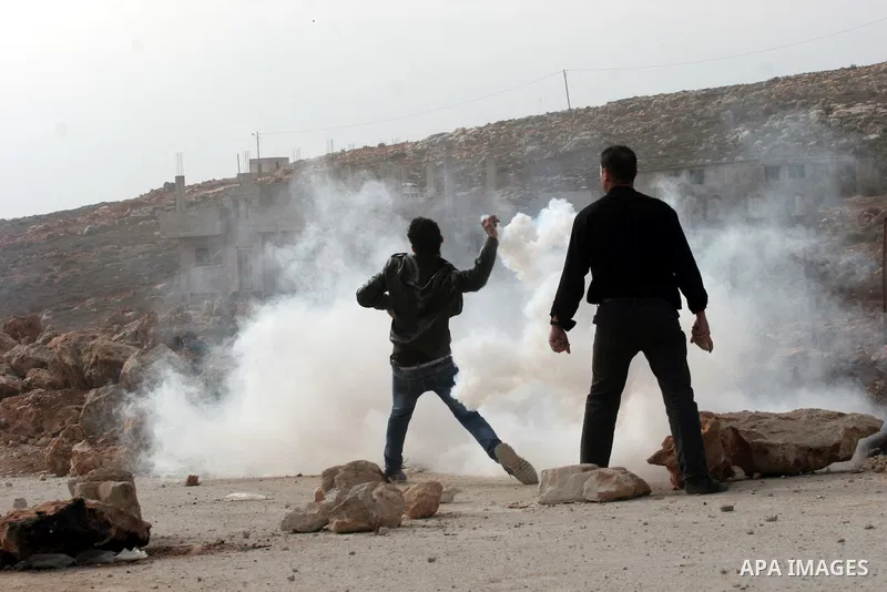 A Palestinian youth throws back a tear gas canister at Israeli soldiers during clashes following a confrontation between Palestinians and Jewish settlers, in the West Bank village of Qusra, near Nablus, November 18, 2013...