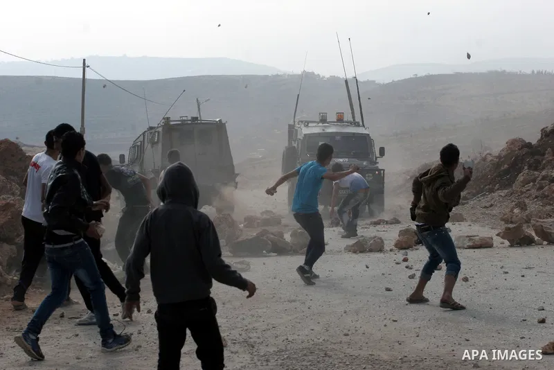 Palestinian youths throw stones at Israeli army jeeps during clashes following a confrontation between Palestinians and Jewish settlers, in the West Bank village of Qusra, near Nablus, November 18, 2013. Jewish settlers...