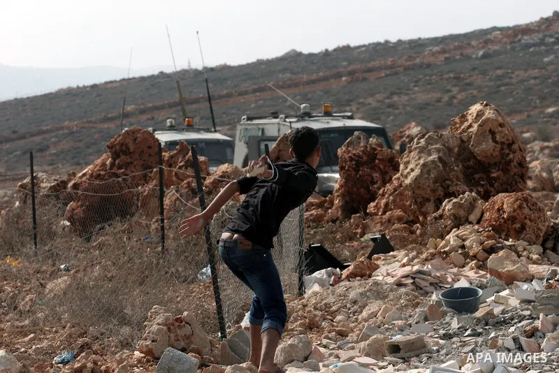 A Palestinian youth throws stones at Israeli army jeeps during clashes following a confrontation between Palestinians and Jewish settlers, in the West Bank village of Qusra, near Nablus, November 18, 2013. Jewish settler...