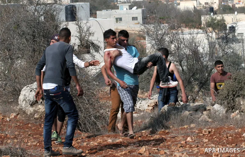 A Palestinian man carries a wounded youth during clashes with Israeli soldiers following a confrontation between Palestinians and Jewish settlers, in the West Bank village of Qusra, near Nablus, November 18, 2013. Jewish...