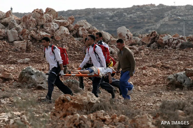 Palestinian medics carry a wounded youth during clashes with Israeli soldiers following a confrontation between Palestinians and Jewish settlers, in the West Bank village of Qusra, near Nablus, November 18, 2013. Jewish...