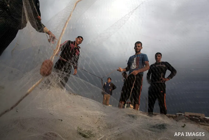 Palestinian fishermen retrieve their net during a rainy day at the beach of Gaza City, on November 18, 2013. Photo by Ashraf Amra