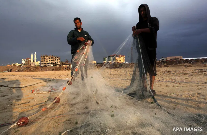 Palestinian fishermen retrieve their net during a rainy day at the beach of Gaza City, on November 18, 2013. Photo by Ashraf Amra
