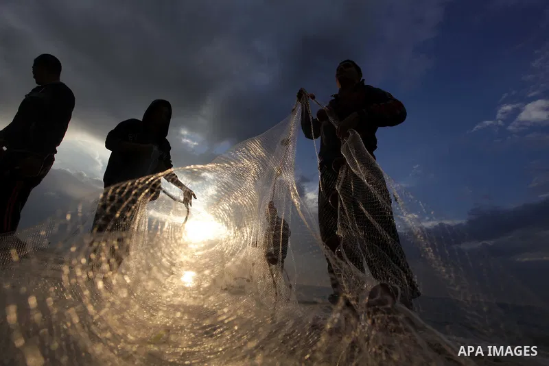 Palestinian fishermen retrieve their net during a rainy day at the beach of Gaza City, on November 18, 2013. Photo by Ashraf Amra