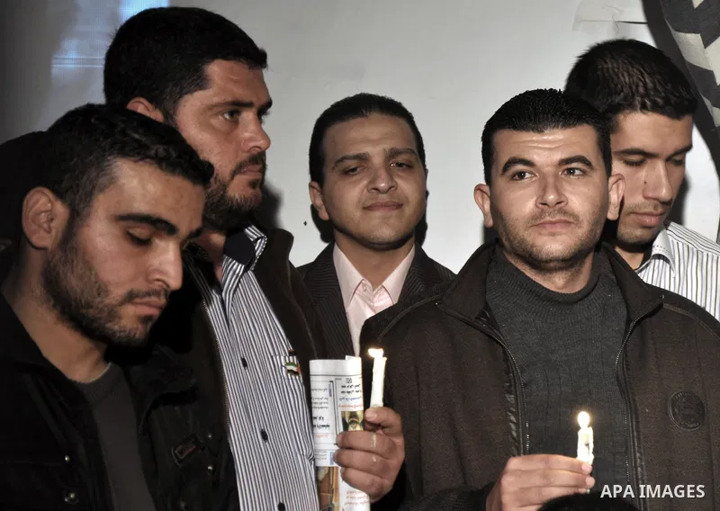 Palestinian journalists hold placards and candles during a protest in solidarity with the local al-Quds TV on the first anniversary of targeting their offices by Israeli warplanes, in Gaza City on November 18, 2013. The...