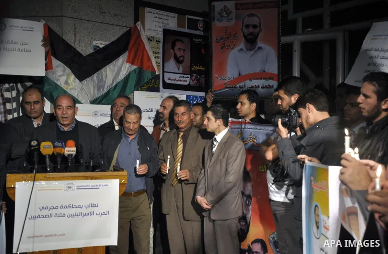 Palestinian journalists hold placards and candles during a protest in solidarity with the local al-Quds TV on the first anniversary of targeting their offices by Israeli warplanes, in Gaza City on November 18, 2013. The...