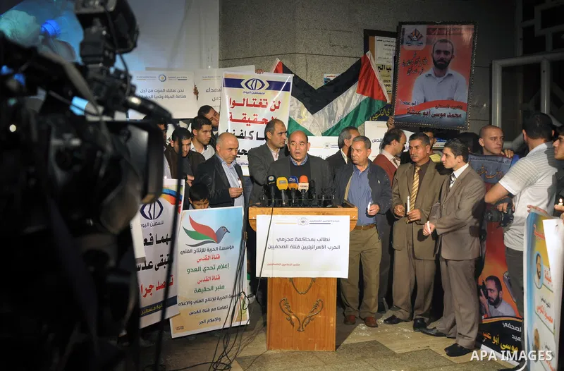 Palestinian journalists hold placards and candles during a protest in solidarity with the local al-Quds TV on the first anniversary of targeting their offices by Israeli warplanes, in Gaza City on November 18, 2013. The...
