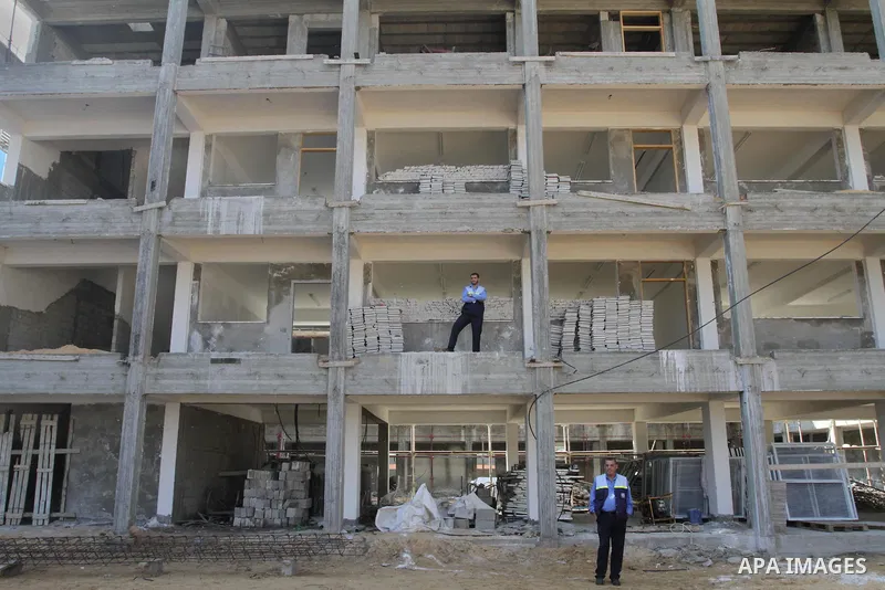 Palestinian men stand on school building in Jabalya in the northern Gaza Strip on Nov. 21, 2013. James Rowley announced the suspension of projects of UNRWA in the Gaza Strip because of the blockade. Photo by Mohammed Asa...