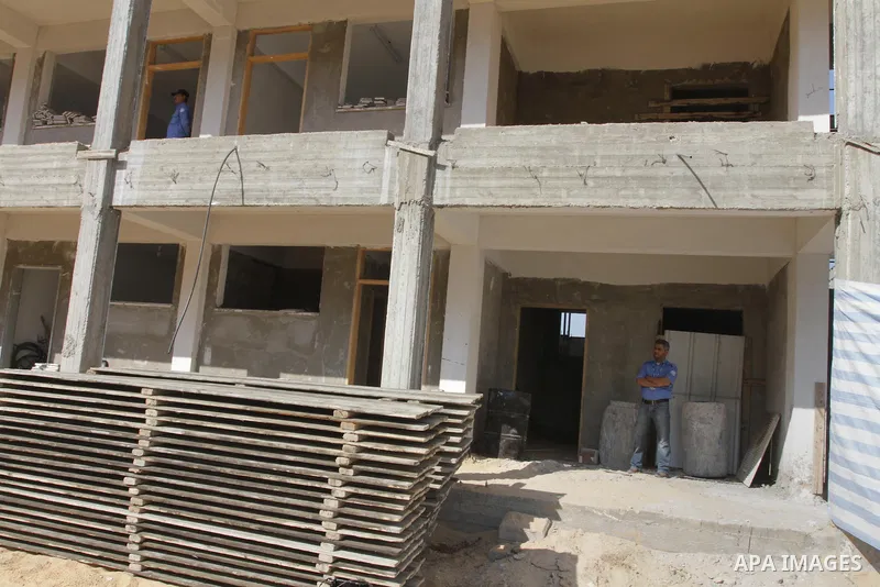 Palestinian men stand on school building in Jabalya in the northern Gaza Strip on Nov. 21, 2013. James Rowley announced the suspension of projects of UNRWA in the Gaza Strip because of the blockade. Photo by Mohammed Asa...