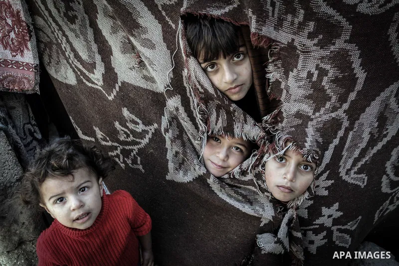 Palestinian children look through a curtain outside their tin shacks in Khan Younis refugee camp, in southern Gaza Strip, November 21, 2013. The UNRWA, which is facing a 36-million dollar deficit, halted 19 out of 20 con...