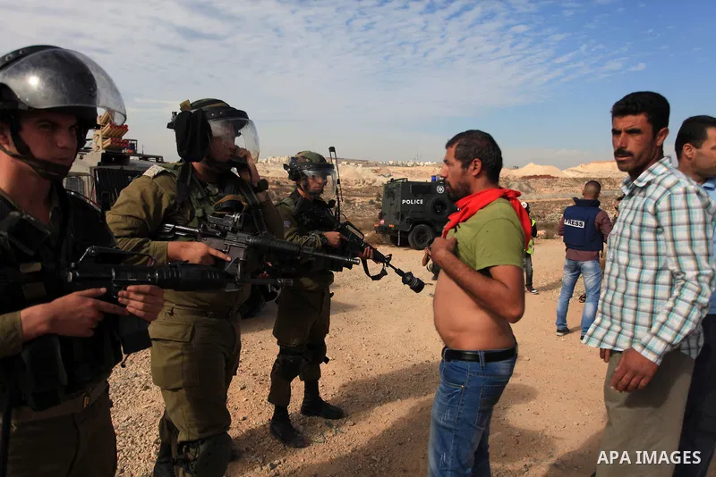A Palestinian man argues with Israeli border policemen during the weekly demonstration against Israel's separation barrier in the West Bank village of Bilin, near Ramallah, Friday, Nov. 22, 2013. Photo by Issam Rimawi
