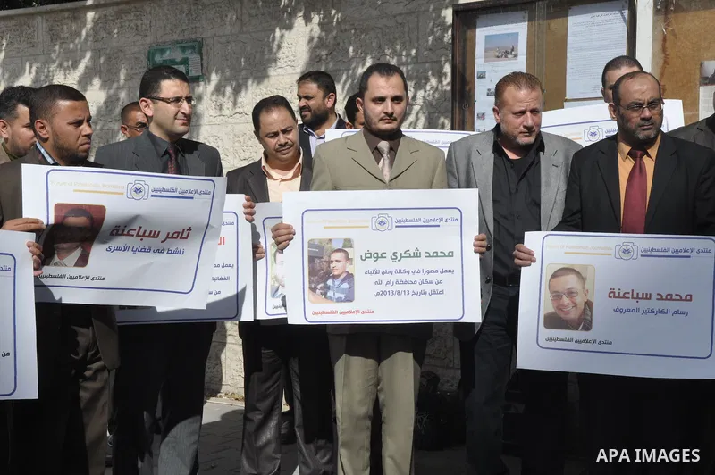 Palestinian journalists carry placards during a protest in solidarity with Palestinian journalists in the West Bank, in front of Red cross in Gaza city, on Nov. 27, 2013. Photo by Mohammed Talatene