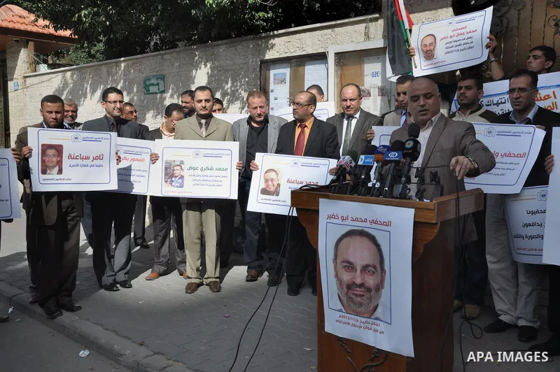 Palestinian journalists carry placards during a protest in solidarity with Palestinian journalists in the West Bank, in front of Red cross in Gaza city, on Nov. 27, 2013. Photo by Mohammed Talatene