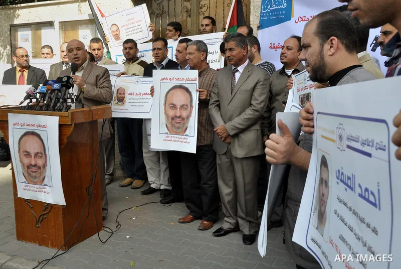 Palestinian journalists carry placards during a protest in solidarity with Palestinian journalists in the West Bank, in front of Red cross in Gaza city, on Nov. 27, 2013. Photo by Mohammed Talatene