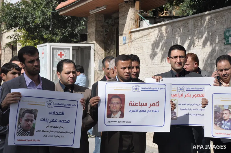 Palestinian journalists carry placards during a protest in solidarity with Palestinian journalists in the West Bank, in front of Red cross in Gaza city, on Nov. 27, 2013. Photo by Mohammed Talatene