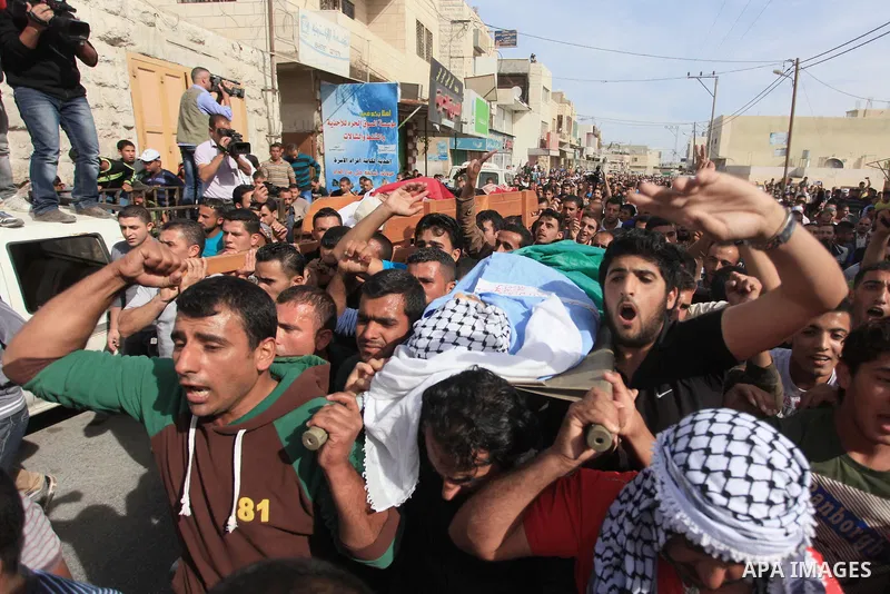 Mourners carry the bodies of Palestinian militants Mahmoud al-Najjar, and Moses Makhamreh, during their funeral on November 27, 2013 in the West Bank village of Yatta, one day after he was shot dead, along with two other...