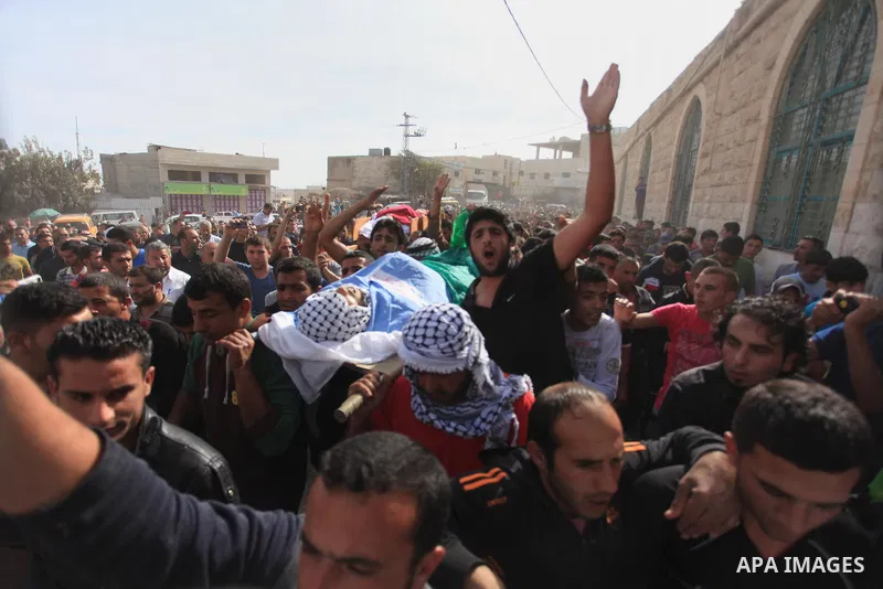 Mourners carry the bodies of Palestinian militants Mahmoud al-Najjar, and Moses Makhamreh, during their funeral on November 27, 2013 in the West Bank village of Yatta, one day after he was shot dead, along with two other...
