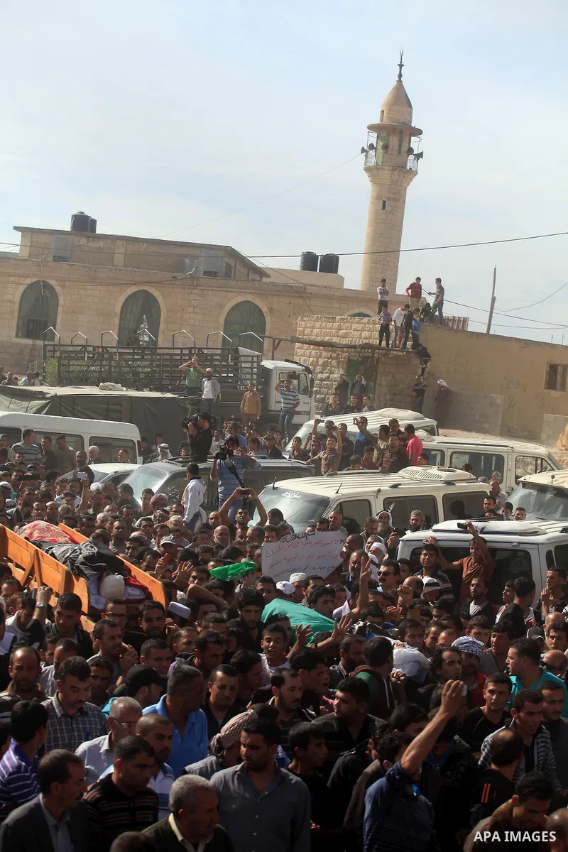 Mourners carry the bodies of Palestinian militants Mahmoud al-Najjar, and Moses Makhamreh, during their funeral on November 27, 2013 in the West Bank village of Yatta, one day after he was shot dead, along with two other...