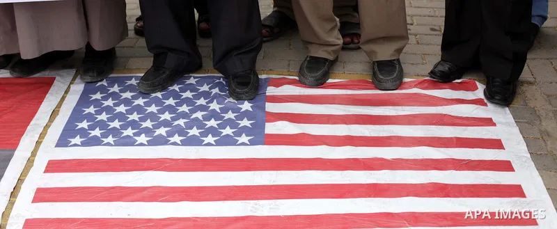 Palestinian protesters stand on a U.S flag during a protest against Angola's government, in Gaza City on November 27, 2013. Angola's government on November 26, 2013 denied it had banned Islam and closed mosques in the co...