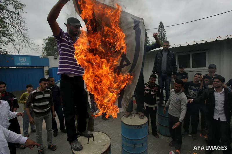 Palestinian protester burn an Israeli flag during a protest against Angola's government, in Gaza City on November 27, 2013. Angola's government on November 26, 2013 denied it had banned Islam and closed mosques in the co...