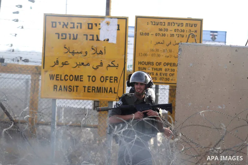 An Israeli security officer takes cover during clashes with students from Bir Zeit University in the West Bank village of Betunia following a protest against the killing of three young Palestinian activists the previous...