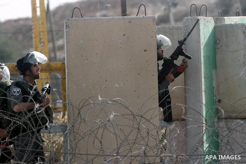 Israeli security officers take cover during clashes with students from Bir Zeit University in the West Bank village of Betunia following a protest against the killing of three young Palestinian activists the previous day...