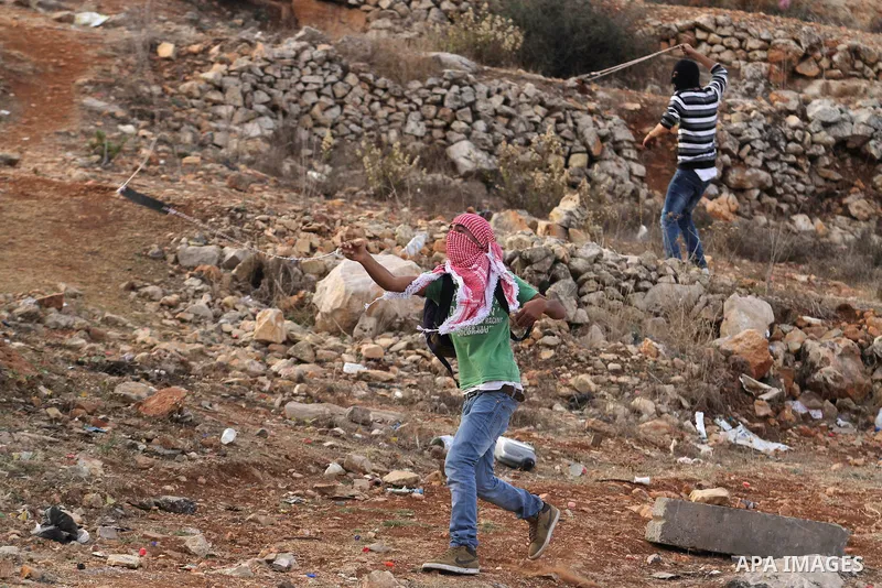 Palestinian protesters hurl stones during clashes between students from Bir Zeit University and Israeli security forces in the West Bank village of Betunia following a protest against the killing of three young Palestini...