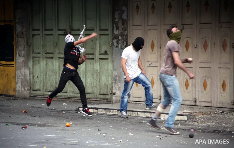 Palestinian protesters throw stones at Israeli soldiers during clashes in the West bank city of Hebron, 27 November 2013. The clashes began after the killing of three Palestinians militants in the West bank village of Ya...