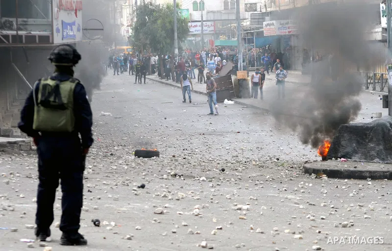 An Israeli soldier takes position as Palestinian protesters throw stones during clashes in the West bank city of Hebron, 27 November 2013. The clashes began after the killing of three Palestinians militants in the West b...