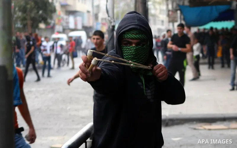 Palestinian protesters throw stones at Israeli soldiers during clashes in the West bank city of Hebron, 27 November 2013. The clashes began after the killing of three Palestinians militants in the West bank village of Ya...