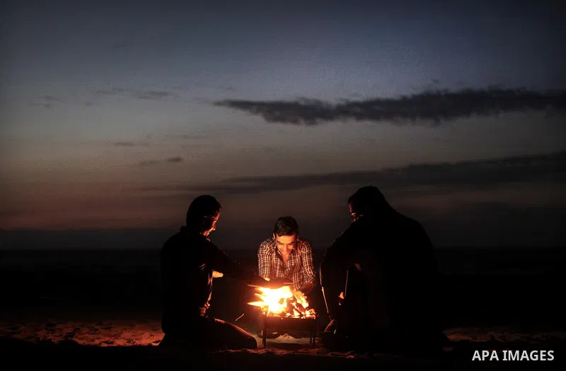 Palestinian youths warm themselves around a firewood at the beach of Gaza City on 28, 2013. The UN started distributing fuel in Gaza to maintain operations of critical facilities amid fears of a health crisis due to gath...
