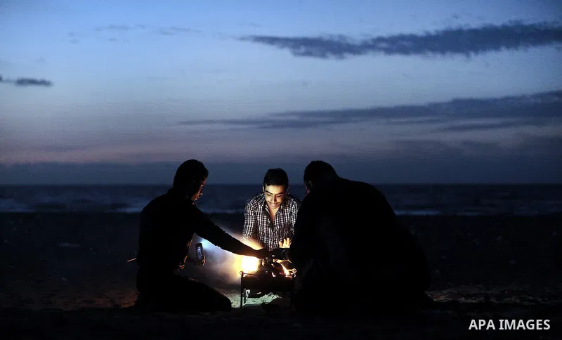 Palestinian youths warm themselves around a firewood at the beach of Gaza City on 28, 2013. The UN started distributing fuel in Gaza to maintain operations of critical facilities amid fears of a health crisis due to gath...