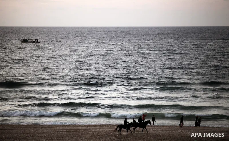 Palestinians walk on the beach of Gaza City on 28, 2013. The UN started distributing fuel in Gaza to maintain operations of critical facilities amid fears of a health crisis due to gathering garbage and sewage, Robert Se...