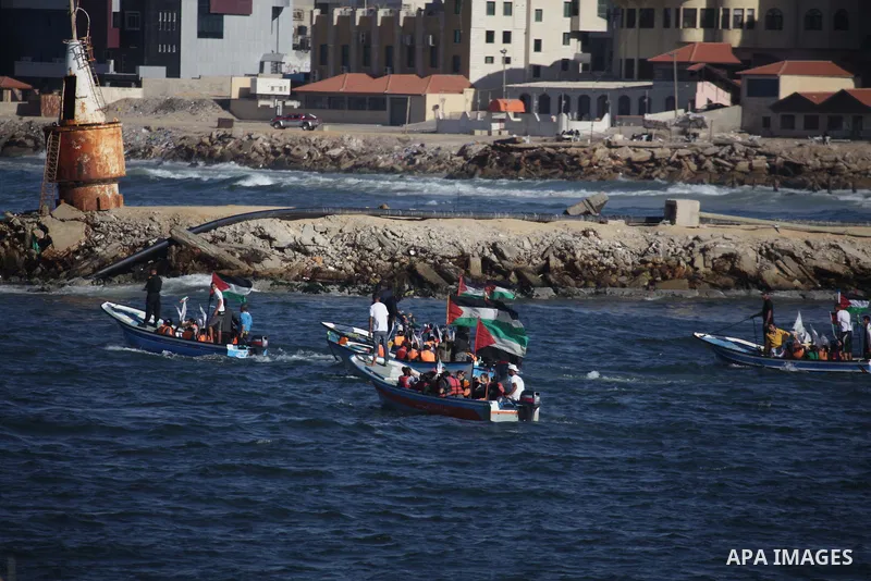 Palestinian children sit on boats before launching in water model boats, with their names and countries' names on sails, during a rally to protest against the Israeli siege of the Gaza Strip on November 30, 2013 at Gaza...