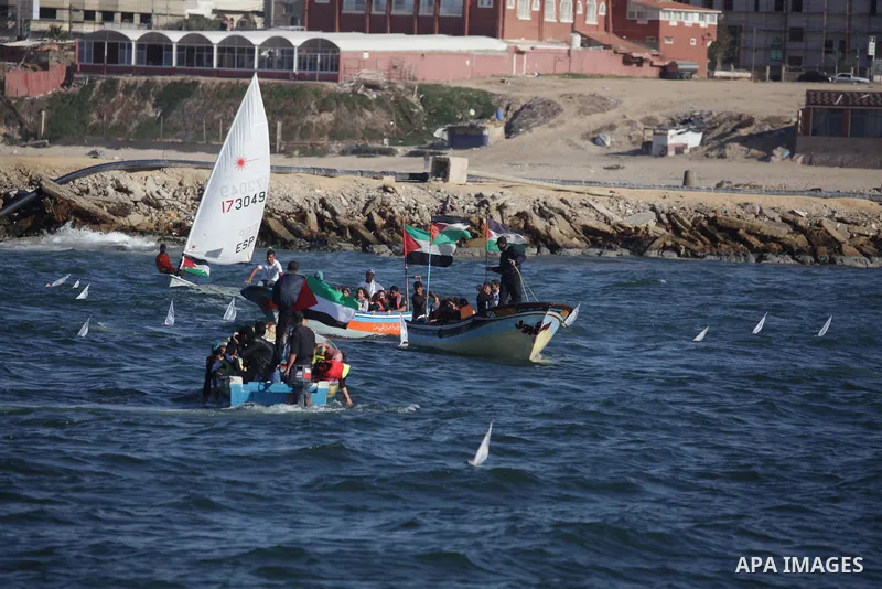 Palestinian children sit on boats before launching in water model boats, with their names and countries' names on sails, during a rally to protest against the Israeli siege of the Gaza Strip on November 30, 2013 at Gaza...