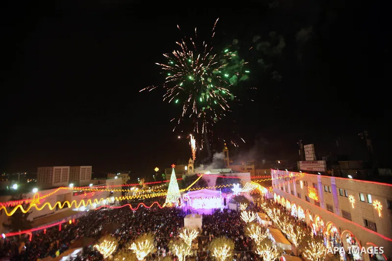 Palestinians celebrate the lighting of the Christmas tree in Manger Square, outside the Church of the Nativity, in the West Bank town of Bethlehem, believed to be the birthplace of Jesus Christ as preparations for Christ...