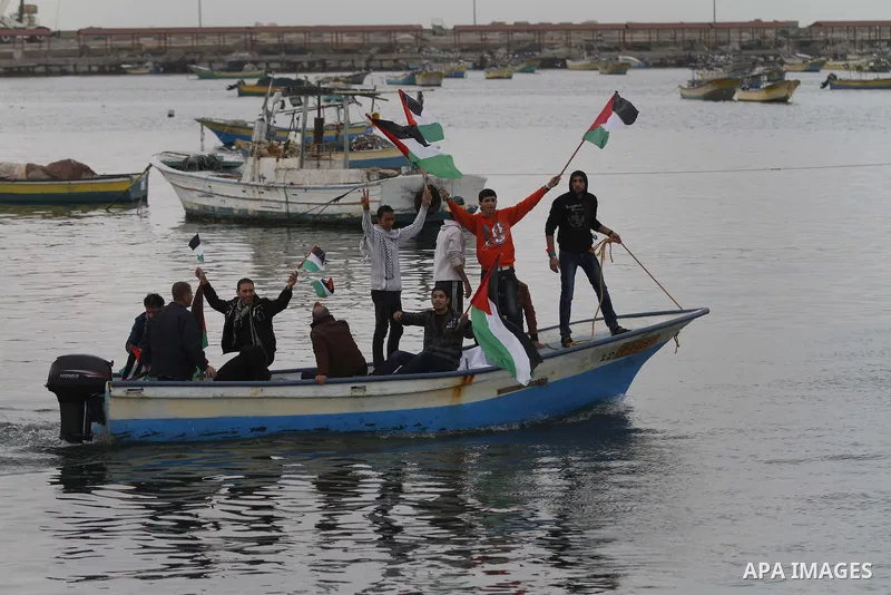 Palestinians sail their boats as part of a convoy that was launched at the initiative of the "Intifada Youth Coalition" (IYC) to break the naval blockade of Gaza as a protest against the Israeli siege on December 2, 2013...