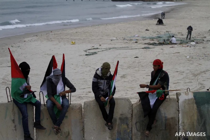 Palestinians pose hold Palestinian national flags before a convoy of boats is launched at the initiative of the "Intifada Youth Coalition" (IYC) to break the naval blockade of Gaza as a protest against the Israeli siege...