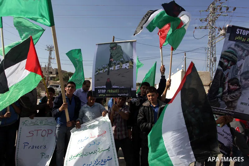 Palestinian protesters hold placards and flags during a protest against the Israeli "Prawer plan" in Gaza City on Dec. 02, 2013. "Prawer plan" is a comprehensive plan approved by Israeli government, one of whose aims is...