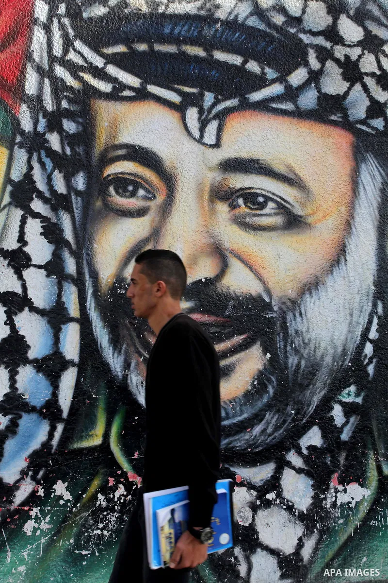 A Palestinian man walks pass a mural shows the late Palestinian leader Yasser Arafat, in Gaza City on Dec. 04, 2013 . Media reports on 03 December 2013 state that late Palestinian leader Yasser Arafat did not die of pois...
