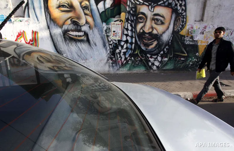 A Palestinian man walks pass a mural shows the late Palestinian leader Yasser Arafat, in Gaza City on Dec. 04, 2013 . Media reports on 03 December 2013 state that late Palestinian leader Yasser Arafat did not die of pois...