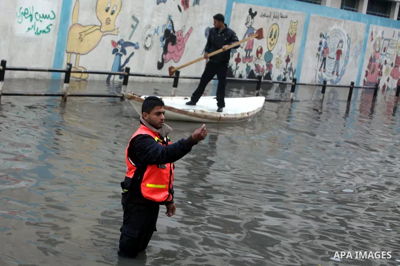 Palestinian civil defense arrive on a boat to help a Palestinian man after his car was submerged in a flooded street following heavy rainfall in Gaza City on December 5, 2013. Photo by Ashraf Amra