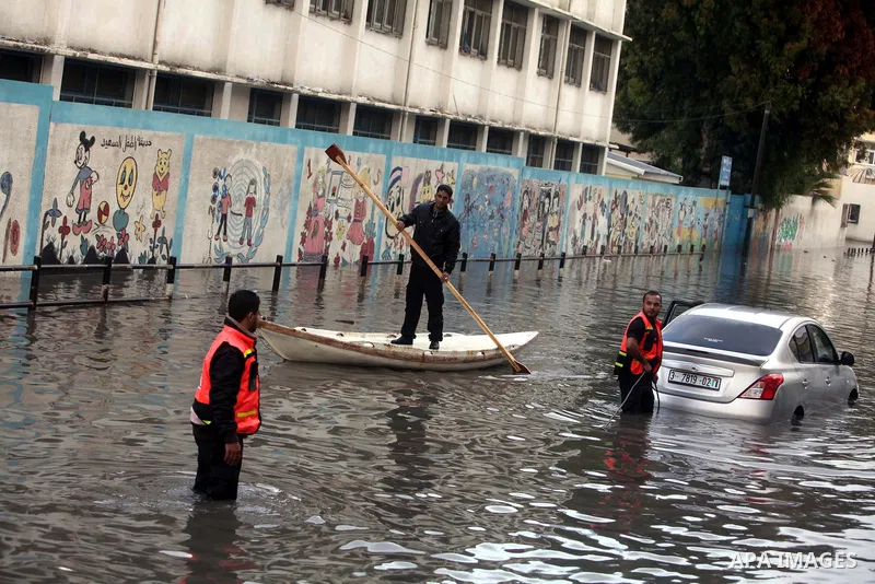 Palestinian civil defence try to remove a car submerged in a flooded street following heavy rainfall in Gaza City on December 5, 2013. Photo by Ashraf Amra
