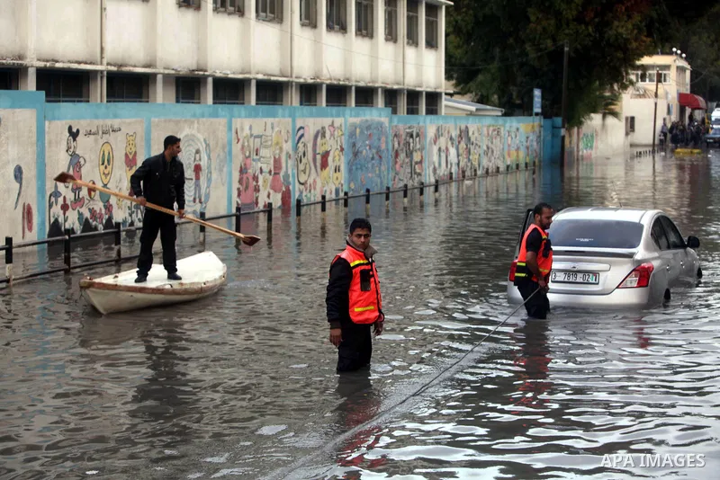 Palestinian civil defence try to remove a car submerged in a flooded street following heavy rainfall in Gaza City on December 5, 2013. Photo by Ashraf Amra