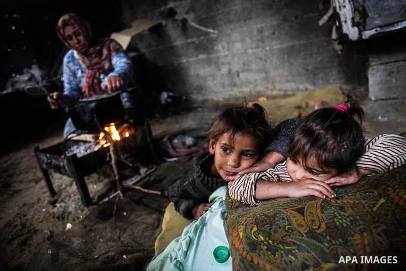 Palestinian children pose as their mother cooks on firewood in their house during a heavy raining day in Beit Lahiya, northern Gaza Strip, Thursday, Dec. 5, 2013. Heavy rains flooded most streets and blocked some of the...