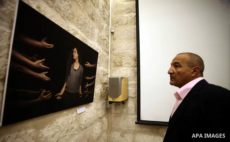 A Palestinian man looks at a photo during a photogallery named 'Room Four', organised by French culture center in Jerusalem on Dec. 05, 2013. The photos by the artist Ashraf Dowani displayed in the photogallery and refle...