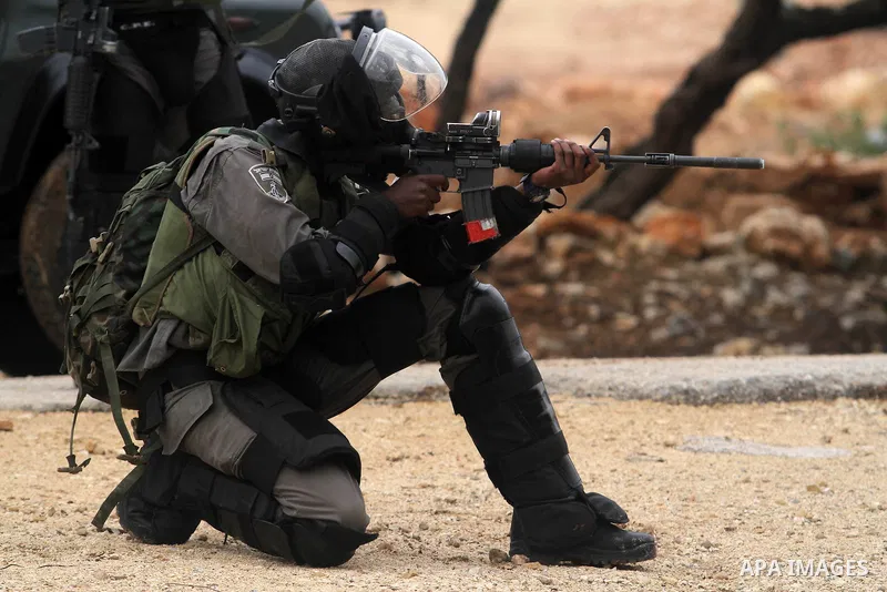 An Israeli soldier rubbers towards Palestinian protesters during clashes following a weekly protest against Israeli occupation in the West Bank village of Bilin on December 6, 2013. US Secretary of State John Kerry urged...