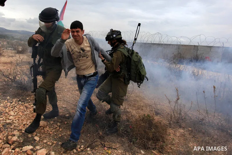 Israeli soldiers detain a Palestinian youth during clashes following a weekly protest against Israeli occupation in the West Bank village of Bilin on December 6, 2013. US Secretary of State John Kerry urged Israeli and P...