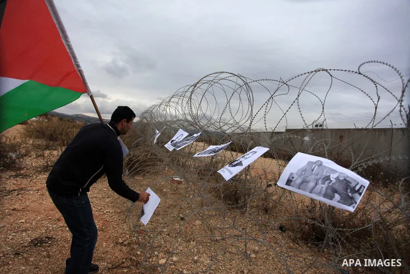 A Palestinian man hangs portraits of late South African president Nelson Mandela on a wire during clashes between youths and the Israeli soldiers following a weekly protest against Israeli occupation in the West Bank vil...